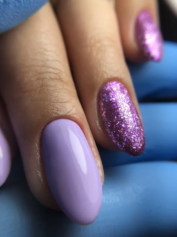 Macro de unha lilás ao lado de unha com glitter rosa